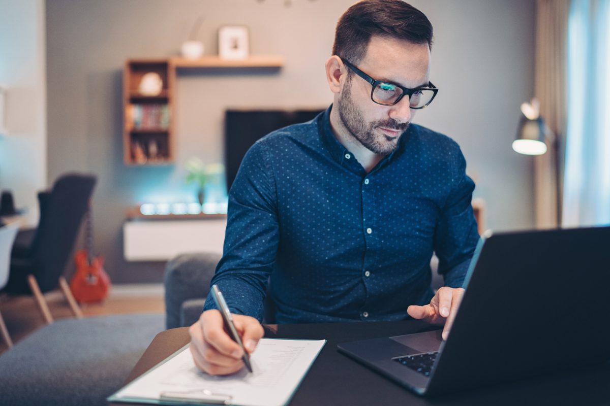 Businessman using laptop and doing paperwork at home