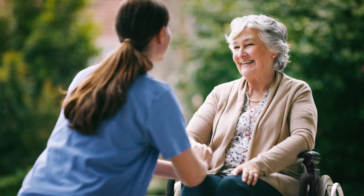 Senior woman in wheelchair being cared for by nurse