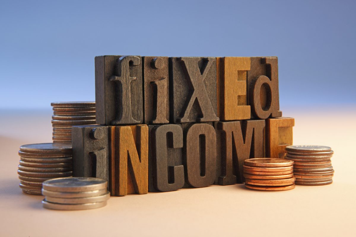 Wooden letter blocks reading fixed income with piles of coins either side