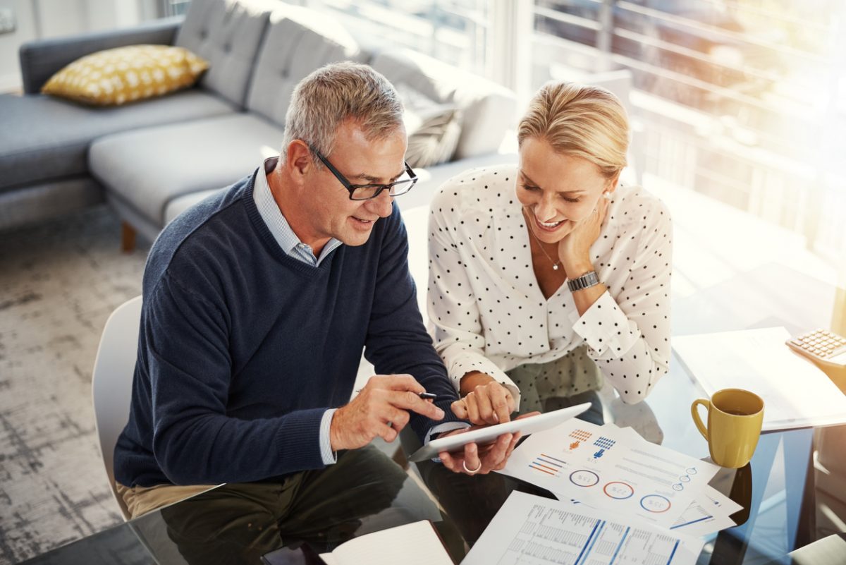 Man and woman at tablet device reviewing finances