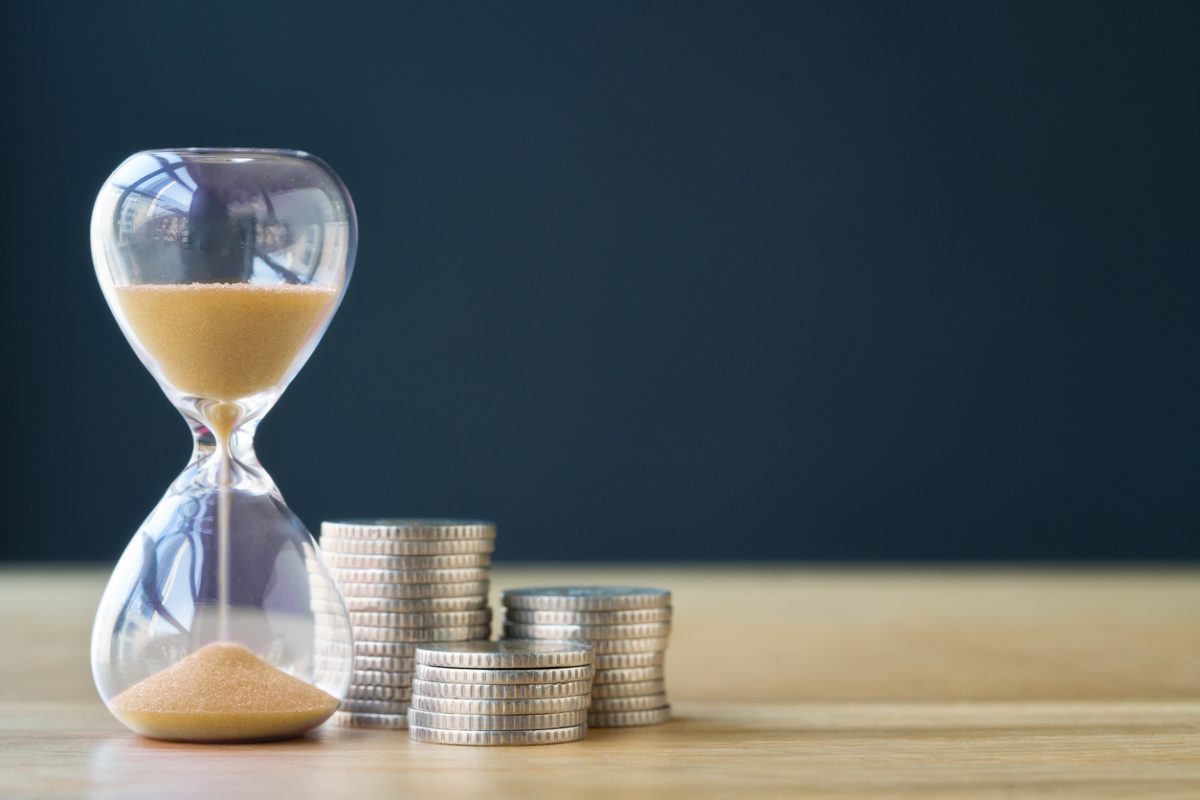 Egg timer running out with a stack of pound coins alongside