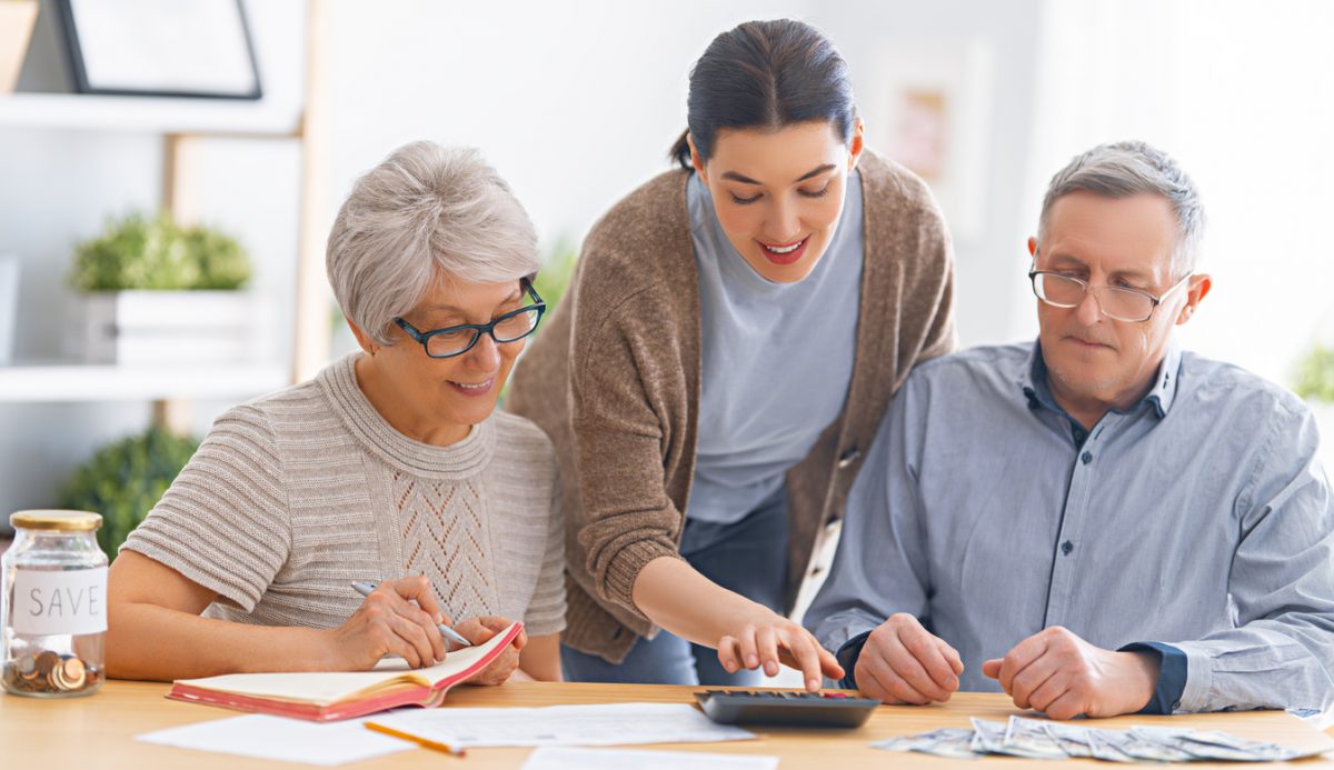 Young woman leans over parents to reach a calculator