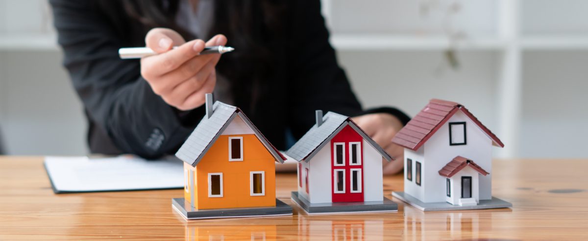 Person analysing finances while looking at icons of three houses representing properties