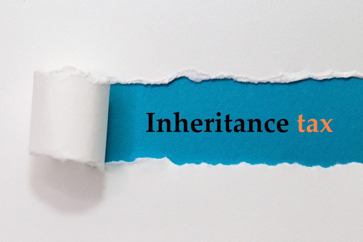 Piece of paper torn back to reveal text on a blue background that reads Inheritance Tax