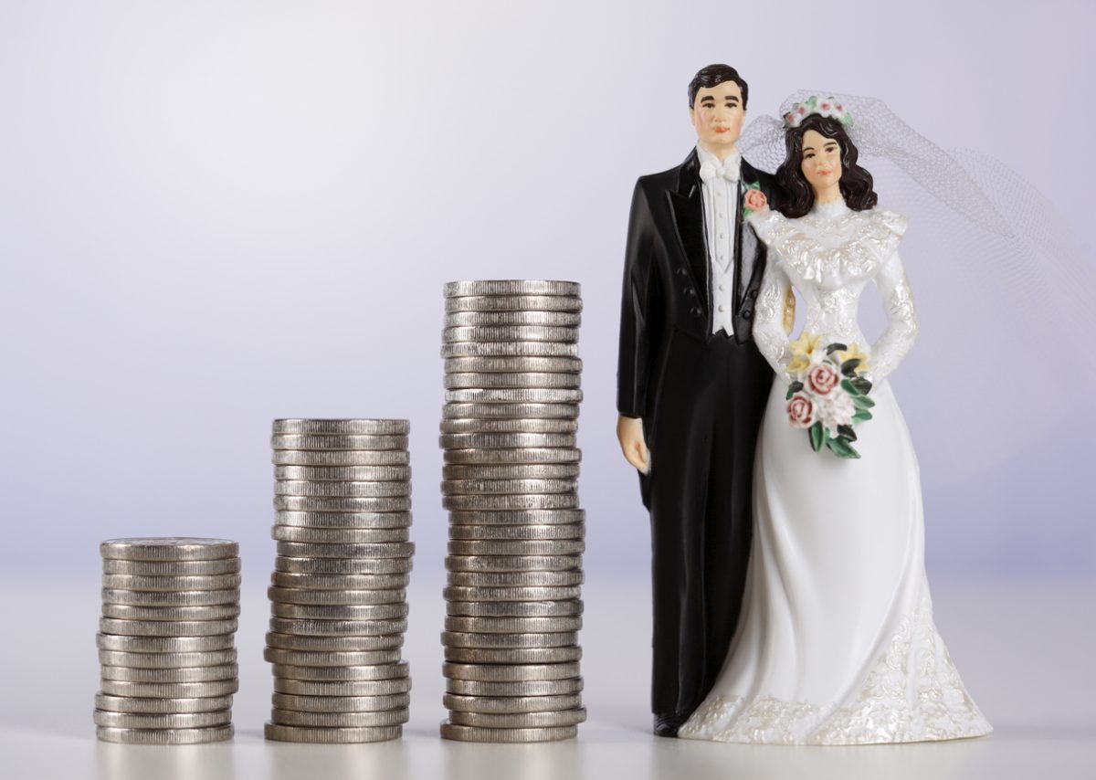 Figurine of bride and groom alongside a pile of coins