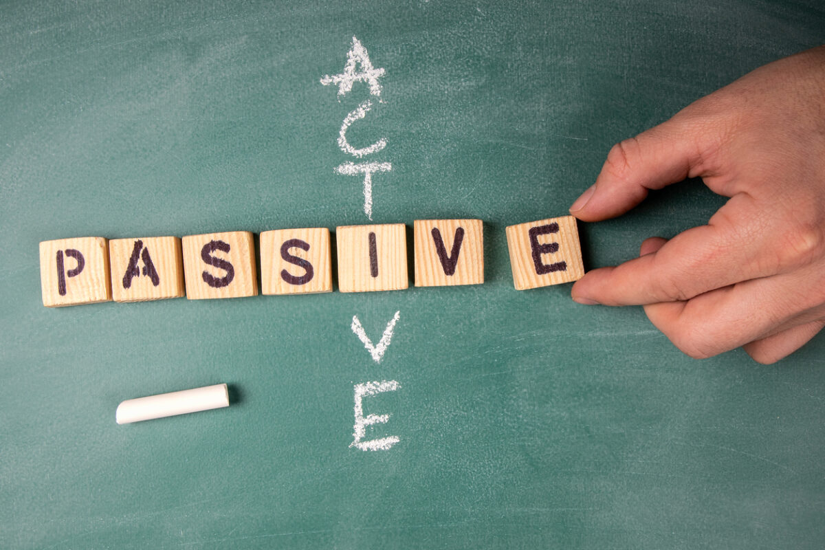 Chalkboard with 'Active' written on it and wooden blocks spelling out 'Passive' representing Active vs Passive fund management